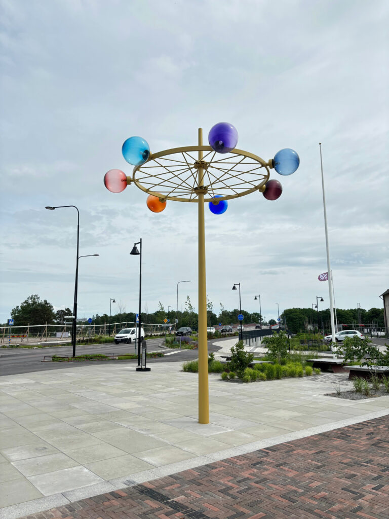 Offentligt konstverk av lackerad stål med sju olikfärgade glasglober.